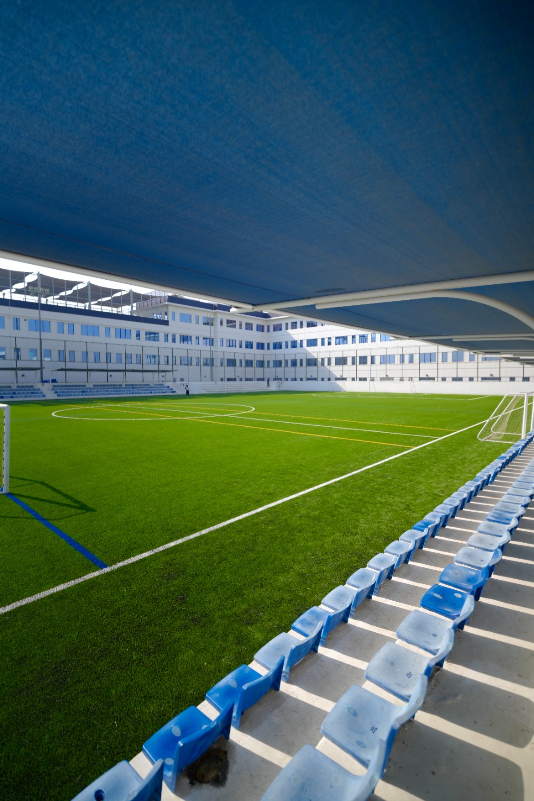Artificial grass football pitch viewed from the shaded spectator seating
